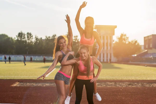 Grupo de mujeres en forma dando paseo a cuestas Felices jóvenes amigos disfrutando de un día en el estadio . — Foto de Stock