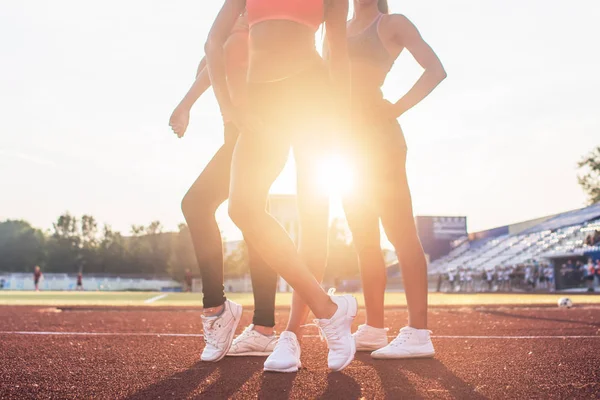 Hermosas piernas de tres atletas en forma de mujeres en el estadio . — Foto de Stock
