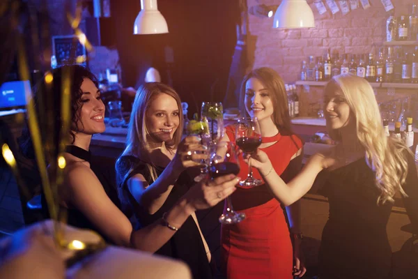 Glückliche junge Frauen mit Weingläsern und Cocktails, die einen Abend in einer stilvollen Bar genießen — Stockfoto