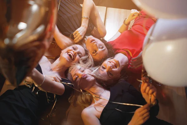 Lachende junge Frauen, die in die Kamera blicken und Luftballons in die Höhe halten — Stockfoto