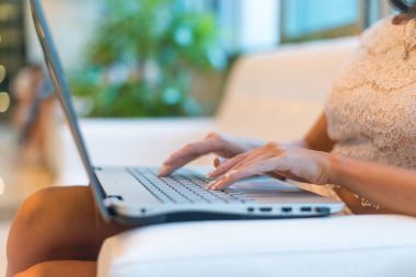 Otel lobi çalışma dizüstü bilgisayar, kanepede oturan genç kadın