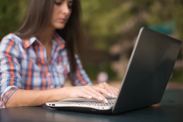 Ung kvinna att skriva på en laptop tangentbord arbetar utomhus — Stockfoto