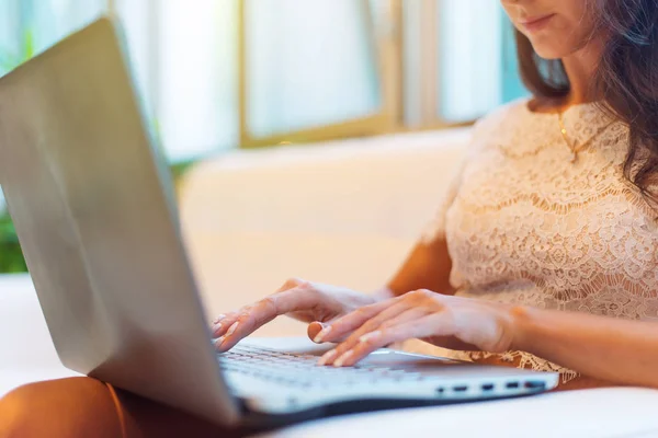Weibliche Hände tippen auf der Tastatur. zugeschnittenes Foto einer jungen Frau, die ihren Laptop in die Knie hält und arbeitet. — Stockfoto
