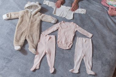 Yatak, doğal ışık ortaya konulan bebek giysileri.