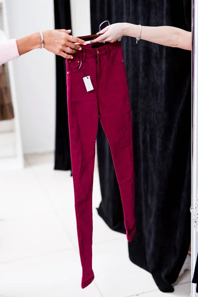 Frauenhände reichen neue Frauen-Jeans an passenden Stand in Einkaufszentrum — Stockfoto