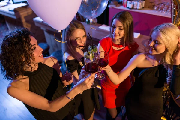 Atrakcyjne młode koleżanki obchodzi stojący wakacje z kieliszków wina w modnym barze — Zdjęcie stockowe
