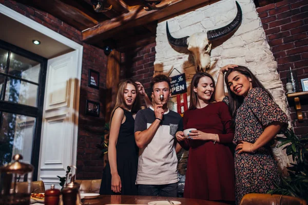 Gruppo di giovani che posano davanti alla telecamera in piedi, sorridendo, ridendo, facendo facce divertendosi nel ristorante alla moda — Foto Stock