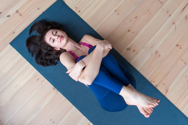 Kameraya bakarak onu bacaklar kucaklayan mat yatarken güzel kumral hoş gülümseyen rahat spotswoman