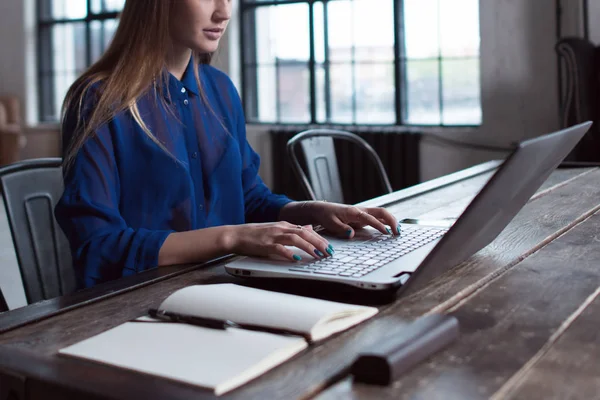 Kobieta z jej ręce na klawiaturze laptopa. Projektanta siedzi worktable z Notatnik i komputer na to. — Zdjęcie stockowe