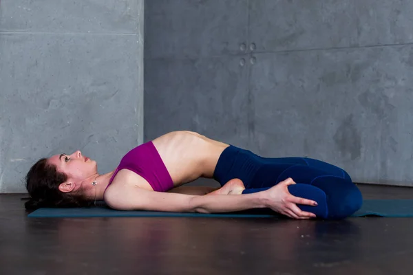Smal ung kvinna liggande i Supta Virasana, reclining Hero Pose, stretching buk- och muskler på matta i gymmet — Stockfoto