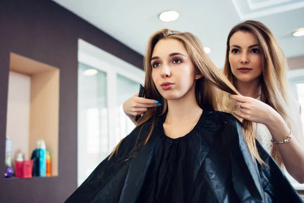 El peluquero que decide con el cliente joven femenino que corte de pelo hacer en la peluquería. Dos guapas rubias discutiendo un nuevo peinado . — Foto de Stock