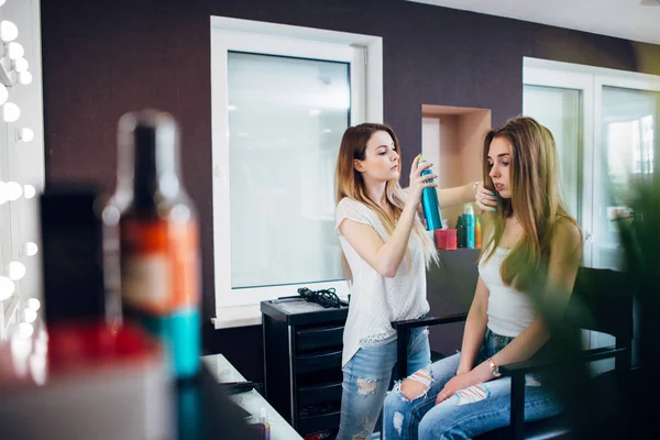 Перукар використовує спрей для волосся на волоссі дівчини, створюючи природну випадкову зачіску в салоні дизайну волосся — стокове фото