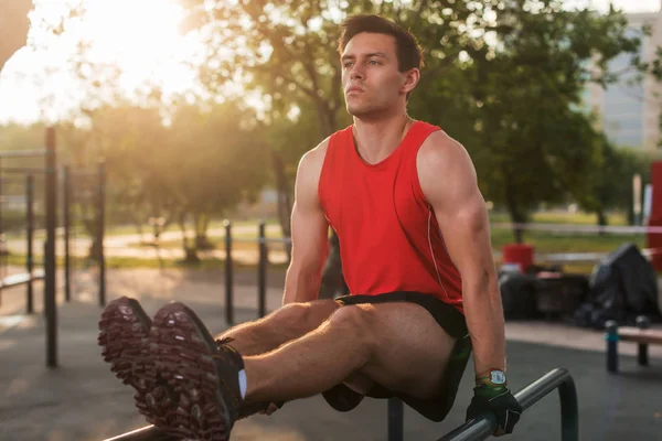 Ajuste hombre realizando levantamientos de piernas en estación de fitness al aire libre . — Foto de Stock