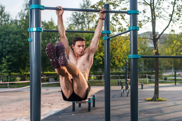 Atleta colgando en estación de fitness realizando levantamientos de piernas. Núcleo de entrenamiento cruzado ejercicios abdominales músculos —  Fotos de Stock