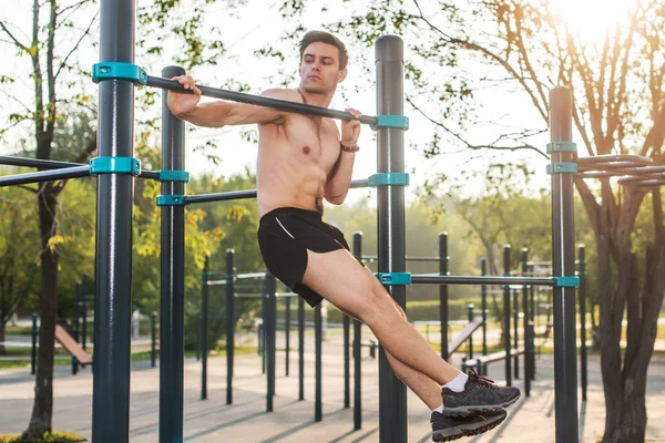 Joven atleta masculino haciendo ejercicios de mentón en el parque. Hombre de fitness haciendo ejercicio afuera —  Fotos de Stock