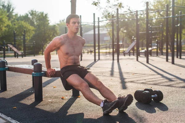 Μικρά ταιριάζει ο άνθρωπος κάνει triceps ντιπ ασκήσεις κατά τη διάρκεια της προπόνηση προπόνηση σε εξωτερικούς χώρους σταυρό. Αρσενικό μοντέλο fitness. — Φωτογραφία Αρχείου