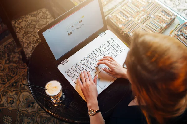 Bovenaanzicht van jonge vrouwelijke student werkt aan laptop zitten aan tafel — Stockfoto