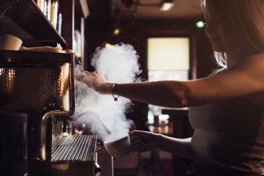 Kadın barista kahve yapma makinesi süt kafede Buhar kullanarak yakın çekim görüntüsü