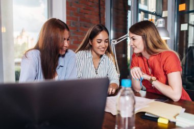 Üç projede sınıfta birlikte çalışan kadın üniversite öğrencileri gülümseyen