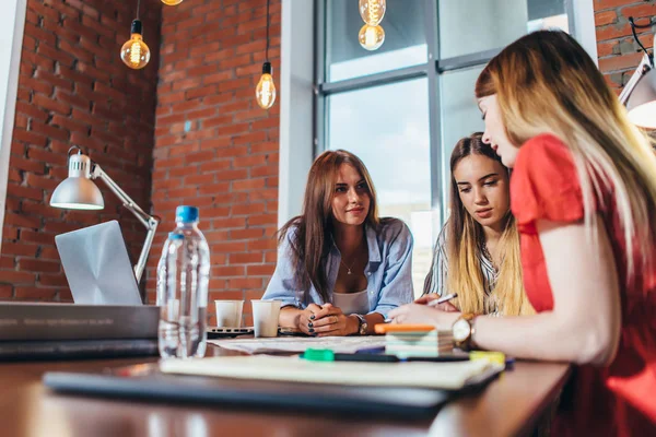 Groep van vrouwelijke collega's werken aan nieuw project zitten aan de balie in creatieve kantoor — Stockfoto