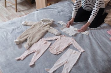 Yatak, doğal ışık ortaya konulan bebek giysileri.