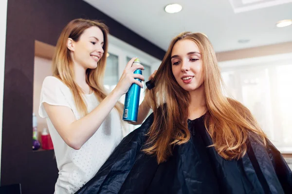 Kapper tot vaststelling van kapsel van lachende vrouwelijke klant met haarspray in schoonheid-kapsalon — Stockfoto