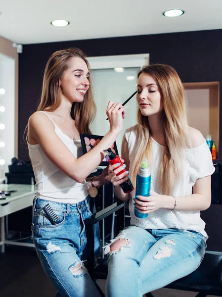 Glada kvinnliga make-up artist ansöker ögonskuggor på hennes vän ögon. — Stockfoto