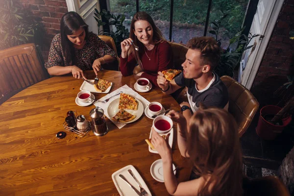 Plan grand angle de groupe de meilleurs amis dînant à table ronde ensemble parlant et souriant dans un café confortable — Photo