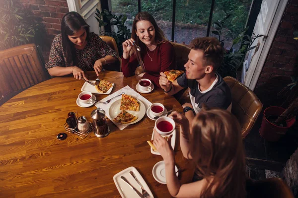 Hoge hoek schot van groep van beste vrienden hebben van diner bij ronde tafel samen praten en glimlachend in het gezellige café — Stockfoto