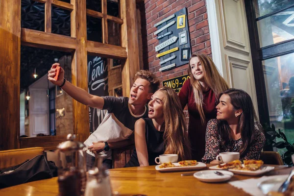 Amici eccitati scattare selfie con smartphone seduto a tavola avendo notte fuori . — Foto Stock