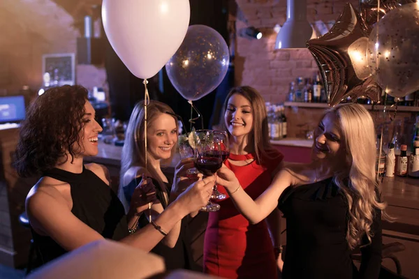 Група веселих дівчат, що проводять вечірку, стоять клінкерні окуляри разом у нічному клубі — стокове фото