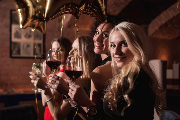 Vrolijke jonge vrouwen staande Terugkijkend naar camera houden glazen wijn viert verjaardag van hun vriendin in restaurant — Stockfoto