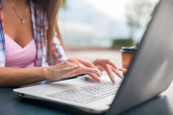 Close up shot of female hands typing on a laptop keyboard. Young woman studying and working in the park — Stock Photo, Image