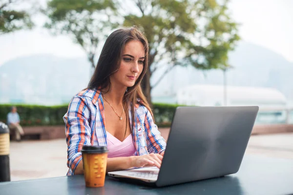 Jovem mulher digitando em um laptop estudando ou trabalhando no parque — Fotografia de Stock