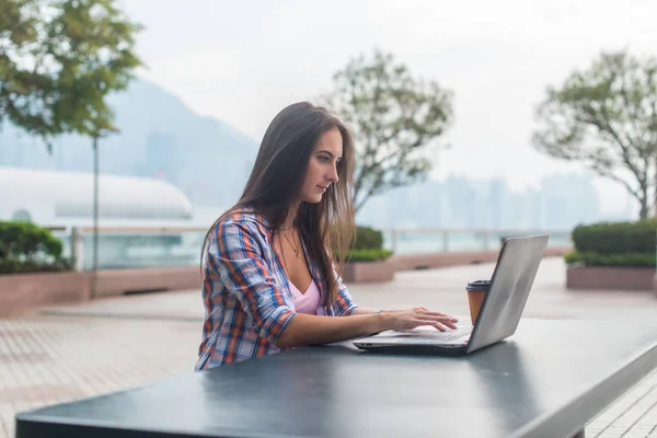 Ung kvinna använder laptop sitter med en kopp kaffe. — Stockfoto
