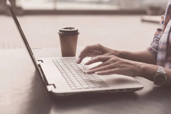 Молода жінка використовує ноутбук, який працює на відкритому повітрі. Жінка дивиться на екран і друкує на клавіатурі . — стокове фото