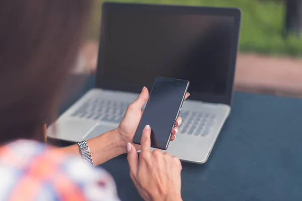 Una giovane donna attraente che legge un messaggio sul suo cellulare. Ragazza seduta all'aperto utilizzando smartphone — Foto Stock