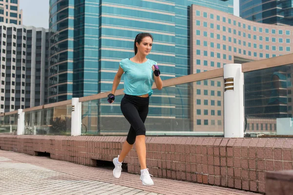 Attractive sporty young woman running on pavement — Stock Photo, Image