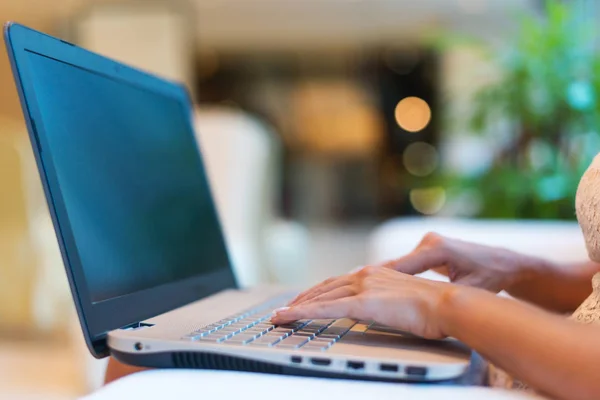 Mãos femininas digitando no teclado. Foto recortada de uma jovem mulher segurando laptop seus joelhos e trabalhando . — Fotografia de Stock