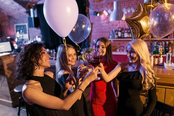 Привабливі молоді друзі-жінки святкують свято, що стоїть в келихах вина в модному барі — стокове фото