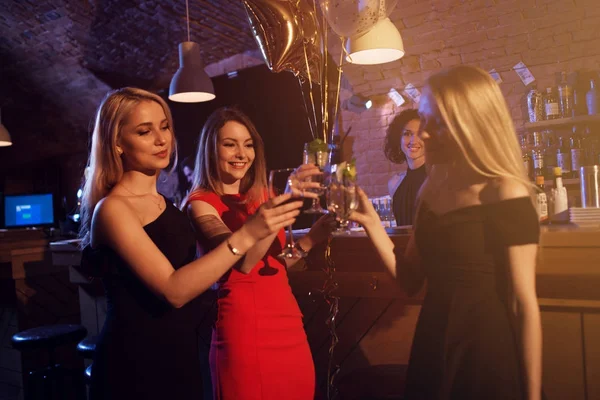 Gelukkig jonge vrouwen met glazen wijn en cocktails genieten van een avondje uit in de stijlvolle bar — Stockfoto
