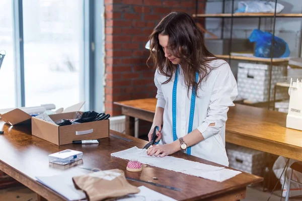 Young female fashion designer cutting fabric with scissors in studio — Stock Photo, Image