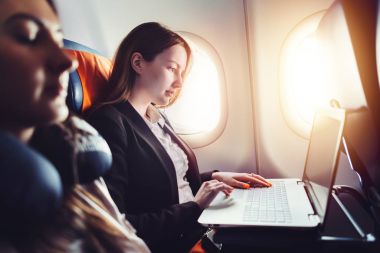 Kadın girişimci bir uçağın penceresinde yakın oturan laptop çalışma