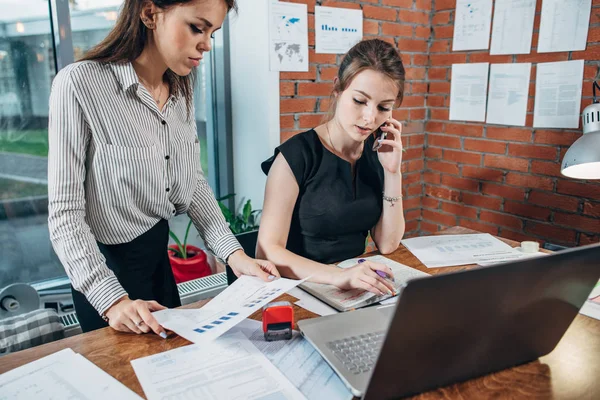 Upptagen kvinna top manager prata i telefon samtidigt som hennes assistent visar hennes finansiell statistik — Stockfoto