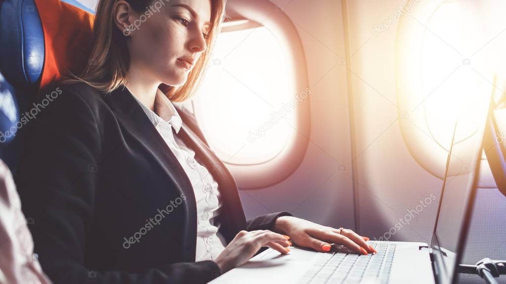 Woman working using laptop while travelling by plane
