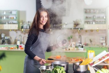 Yemek tarifi kitabı daimi mutfak takip spagetti yemek yaparken önlük giyen genç ve güzel kadın