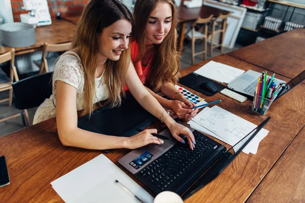 Dos estudiantes sonrientes haciendo tareas juntas usando un portátil sentado en la sala de estudio — Foto de Stock