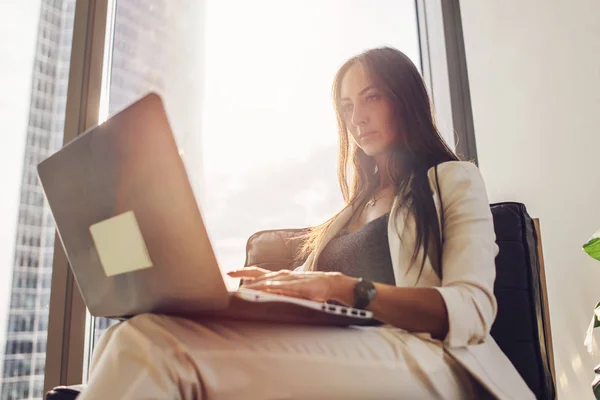 Молода жінка працює на ноутбуці, сидячи вдома — стокове фото