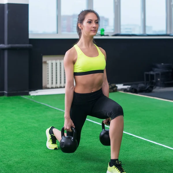 Retrato de una mujer deportiva haciendo embestidas con pesas, ejercitando los músculos de las piernas —  Fotos de Stock