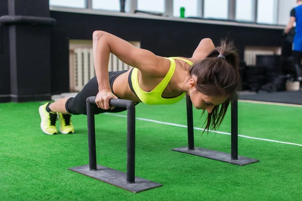 Junge, fitte Frau macht horizontale Liegestütze mit Stangen im Fitnessstudio. — Stockfoto